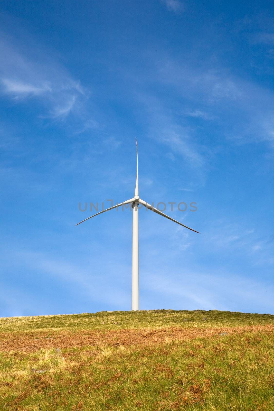 Wind tower on a field with blue sky.