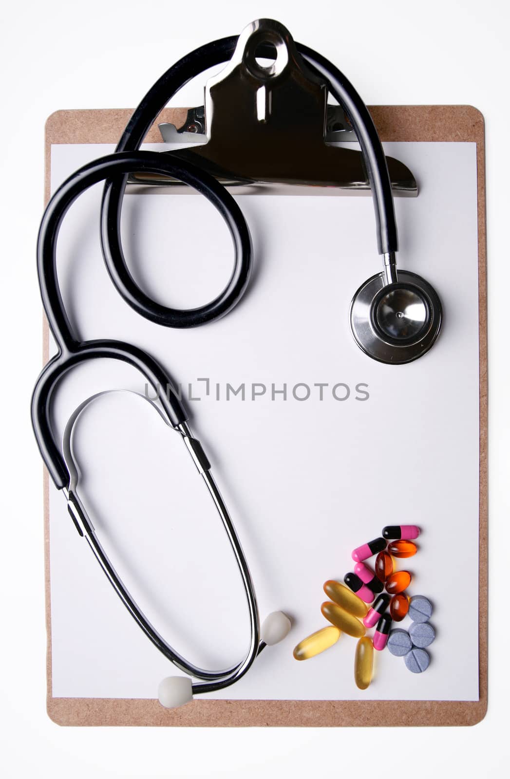 Stethoscope and medicine on clipboard with blank sheet of paper