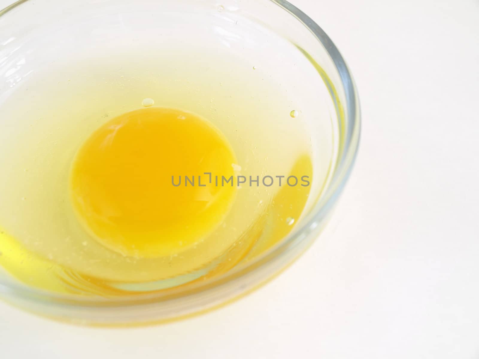 A raw egg cracked in a glass dish. Studio isolation.