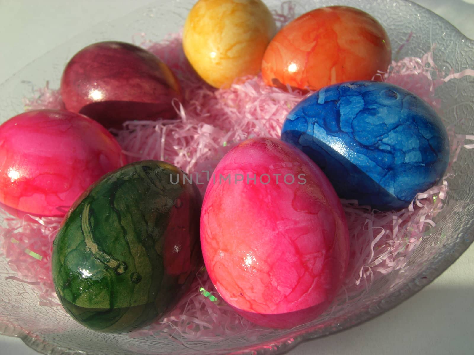 some brightly-painted Easter eggs on a glass dish