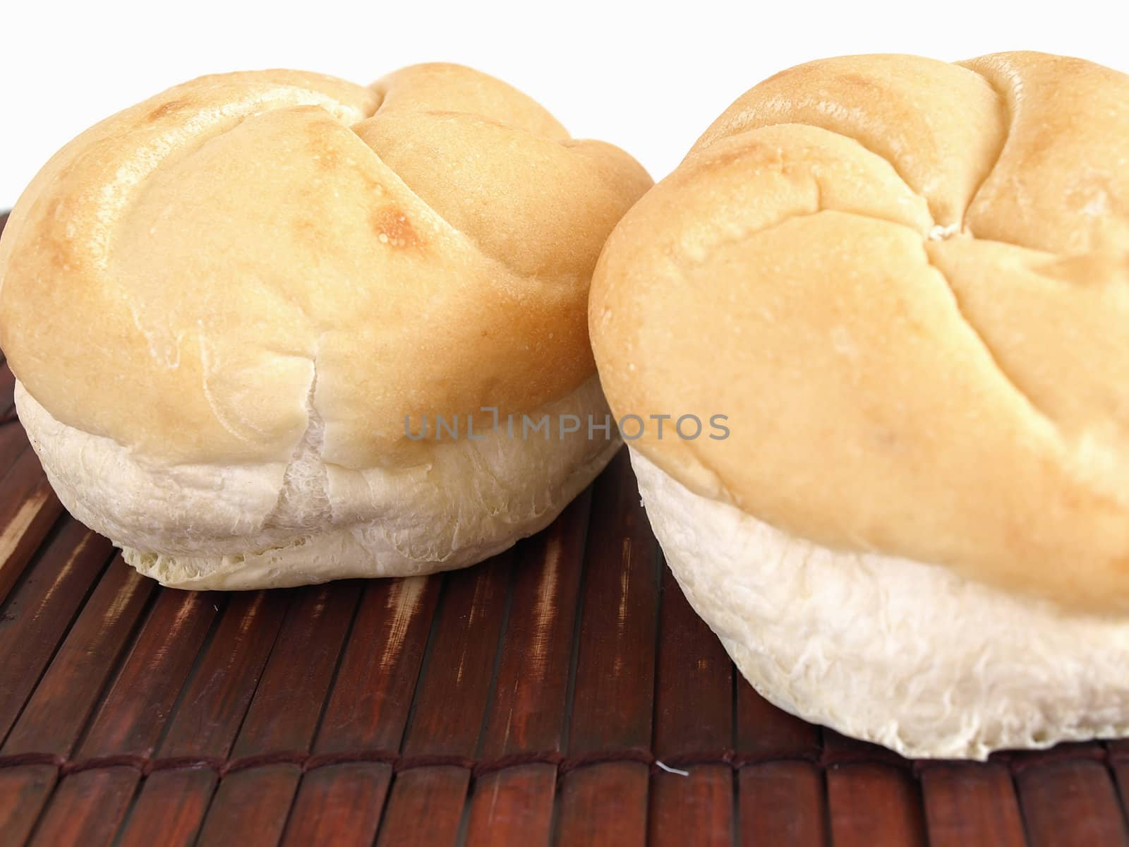 Fresh rolls of bread on a bamboo mat. Studio isolated over white.