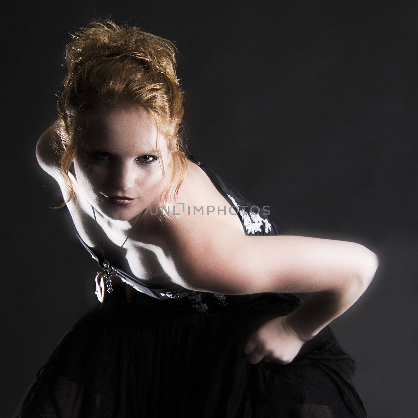 Studio portrait of natural red haired beauty bending towards the camera