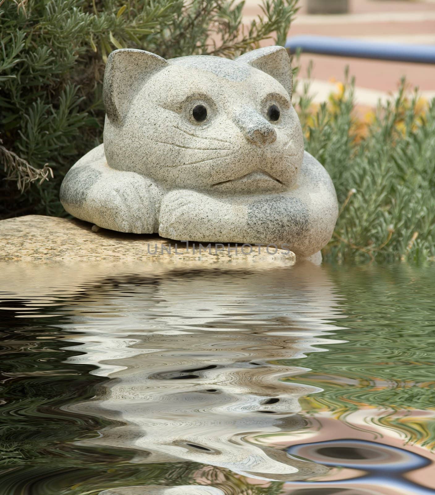 Garden sculpture. Stone cat and its reflection in a reservoir