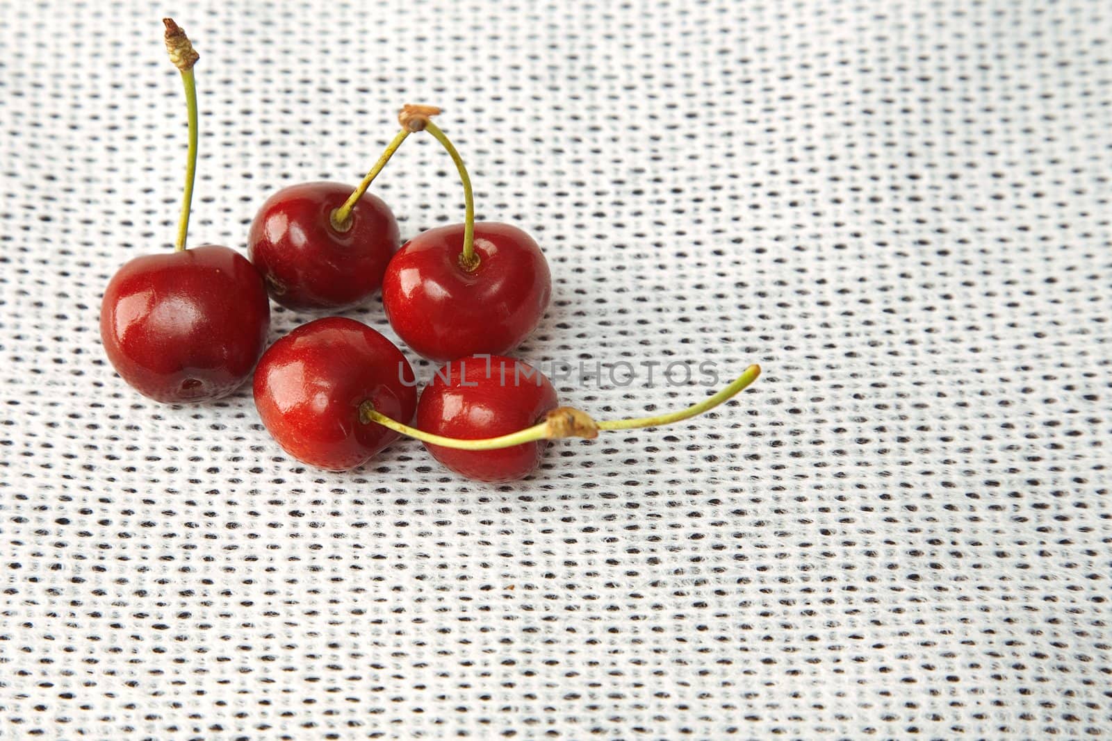 front view of sweet red cherries on white fabric