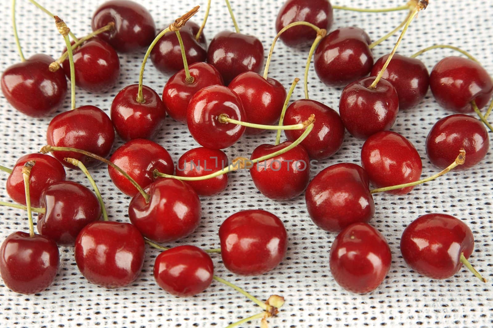 front view of sweet red cherries on white fabric