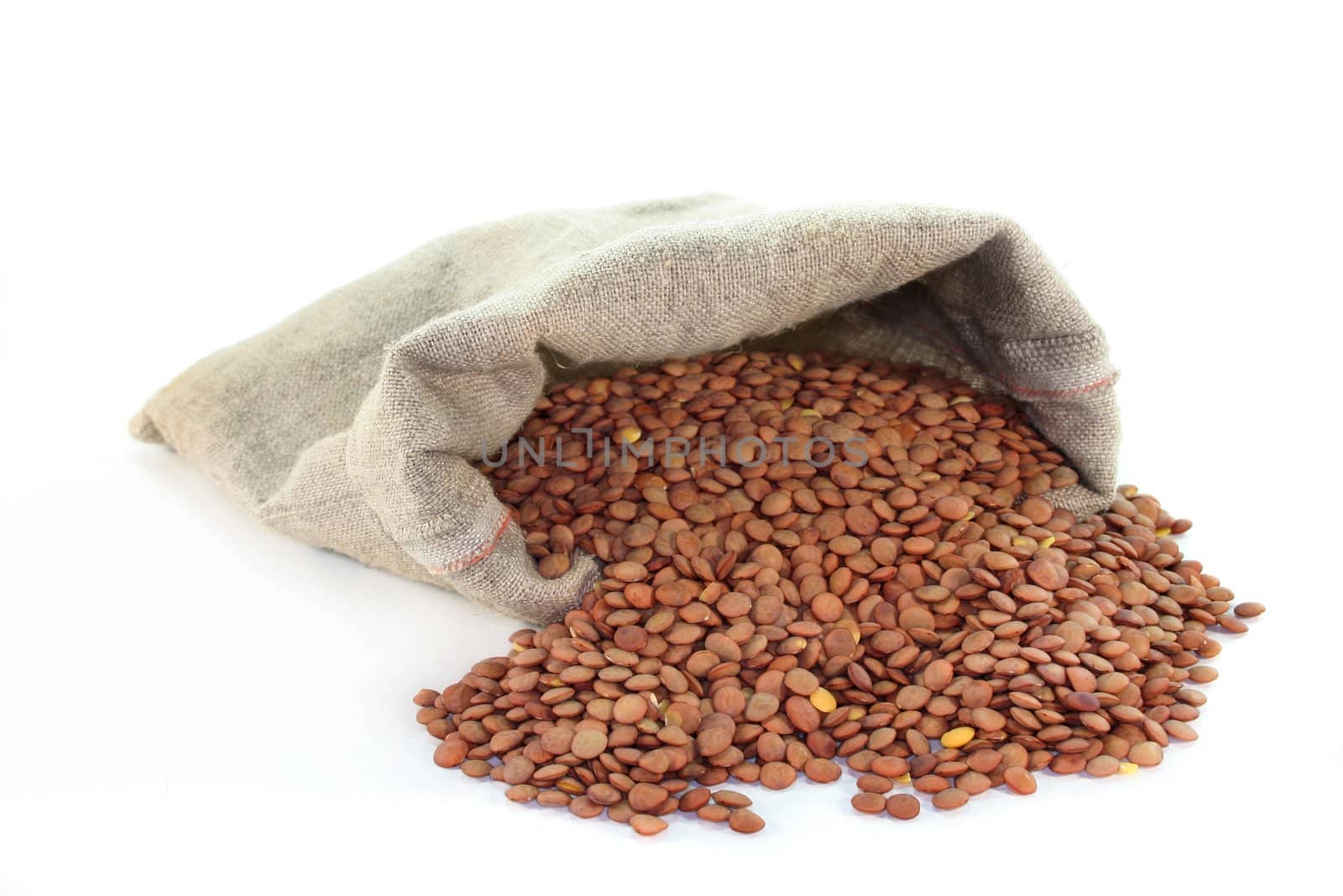 dried lentils in a jute sack on a white background