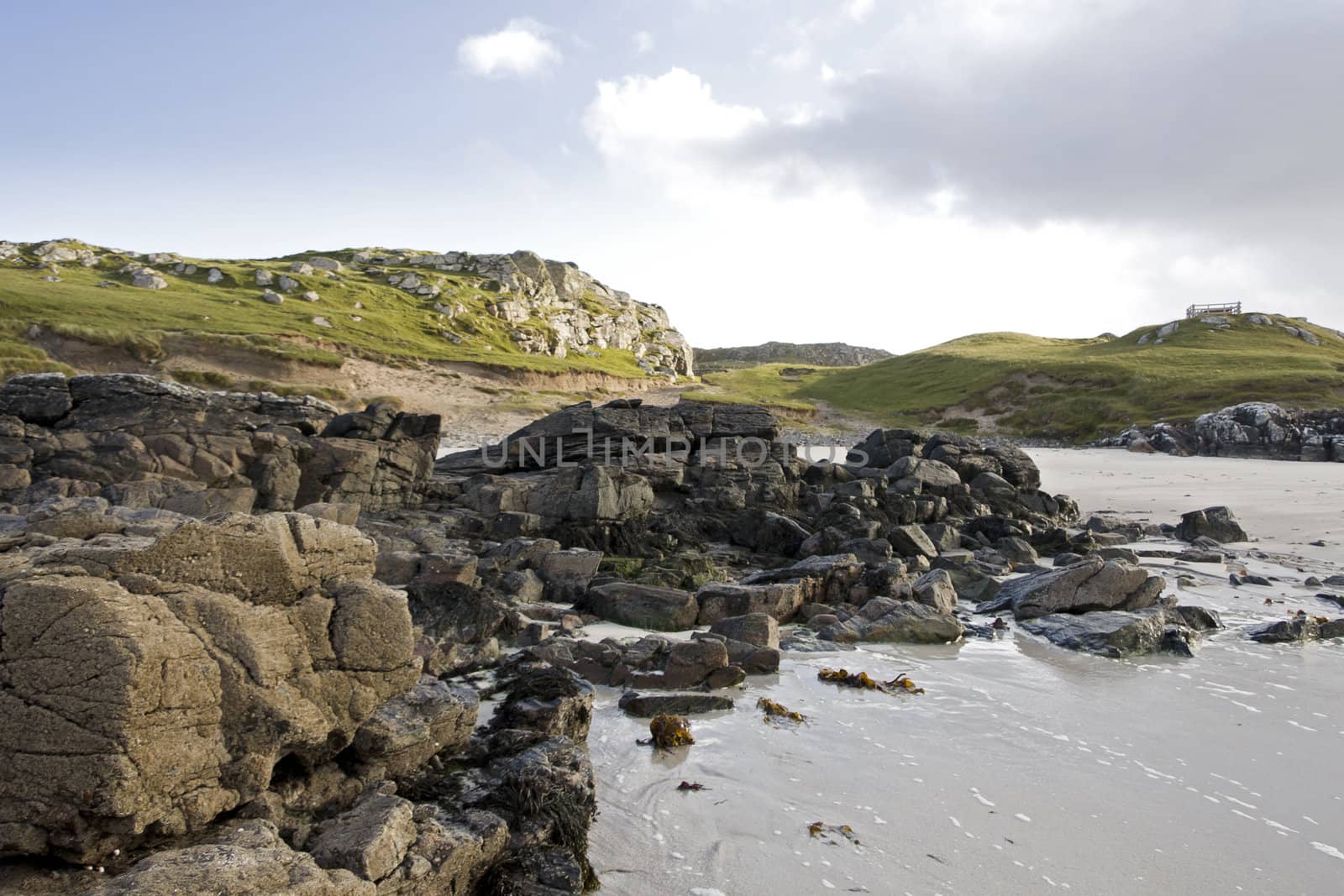 coastal landscape in west scotland. rough stones and green meadow in background