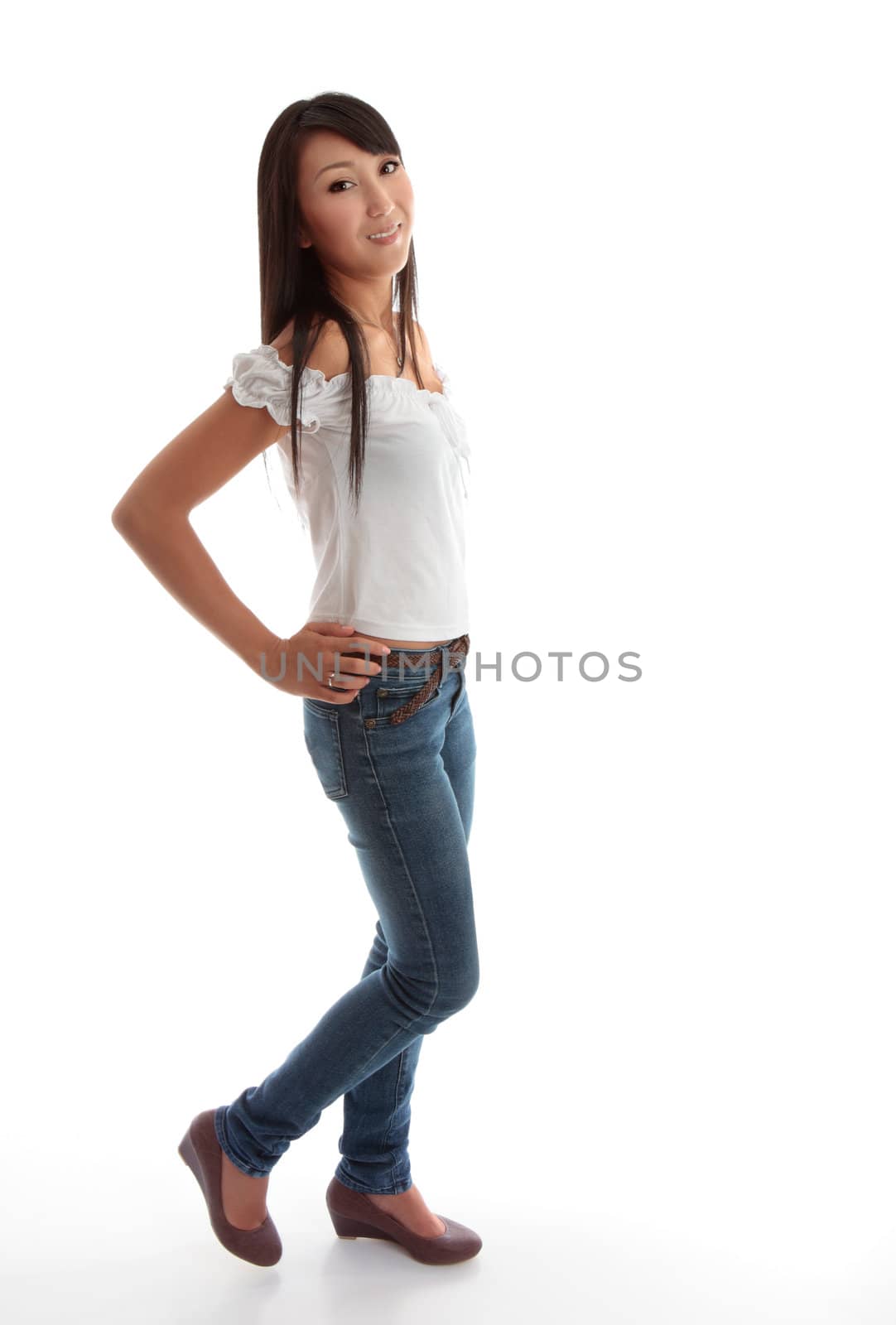 Beautiful young girl wearing skinny leg denim jeans and a white ruffled top.
