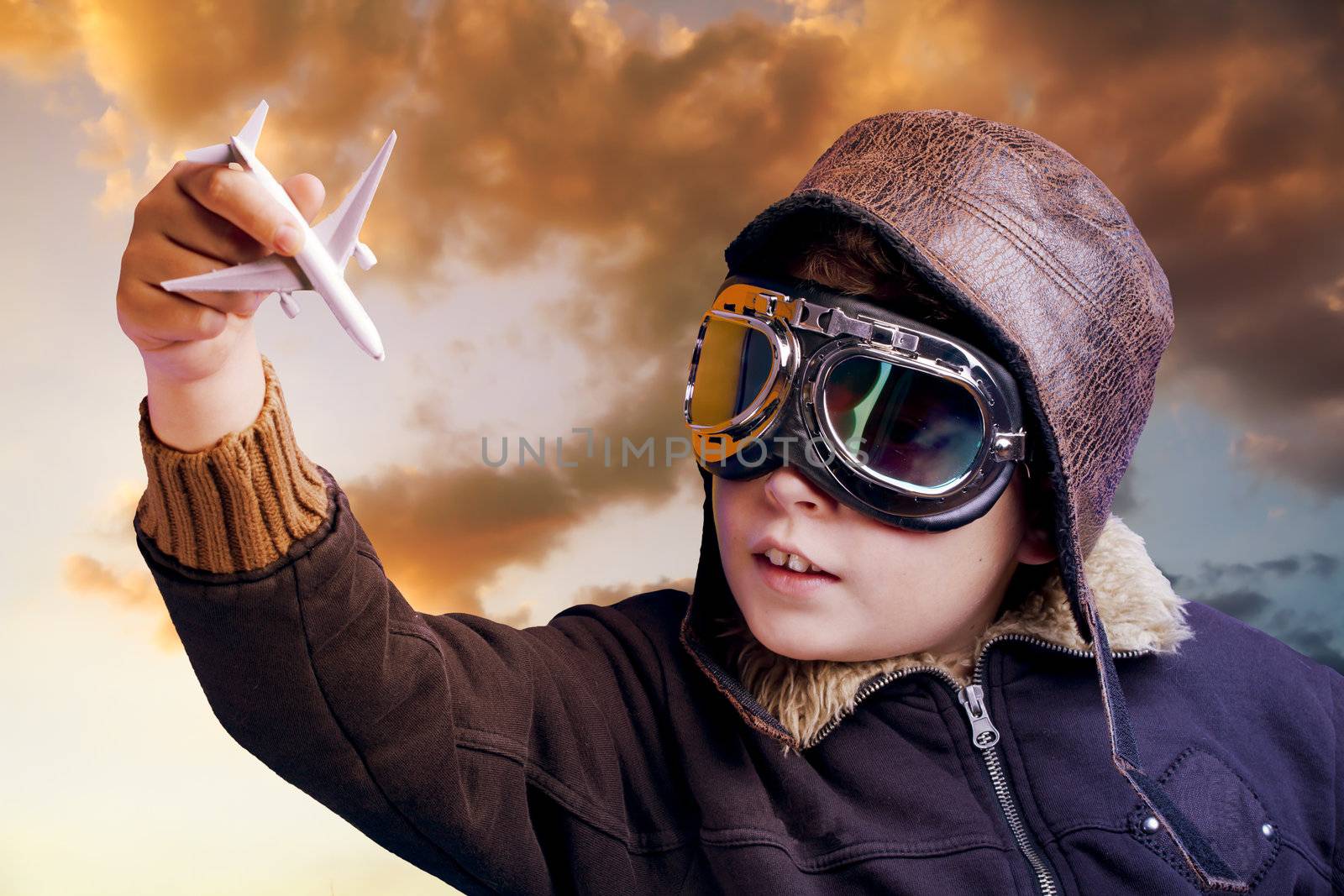 Boy dressed up in pilot outfit at sunset sky