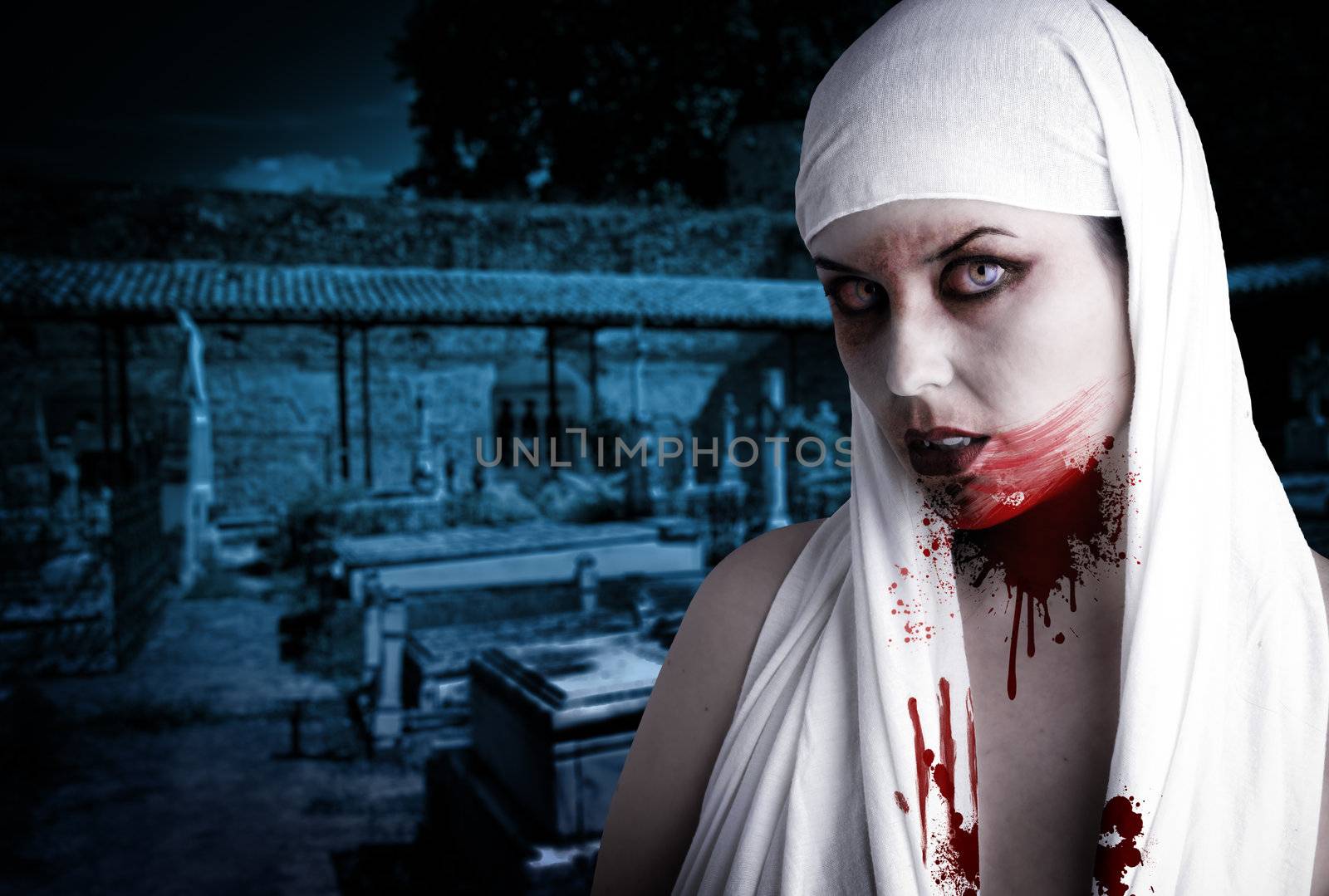 Female vampire with blood stains in a cemetery. Gothic Image halloween