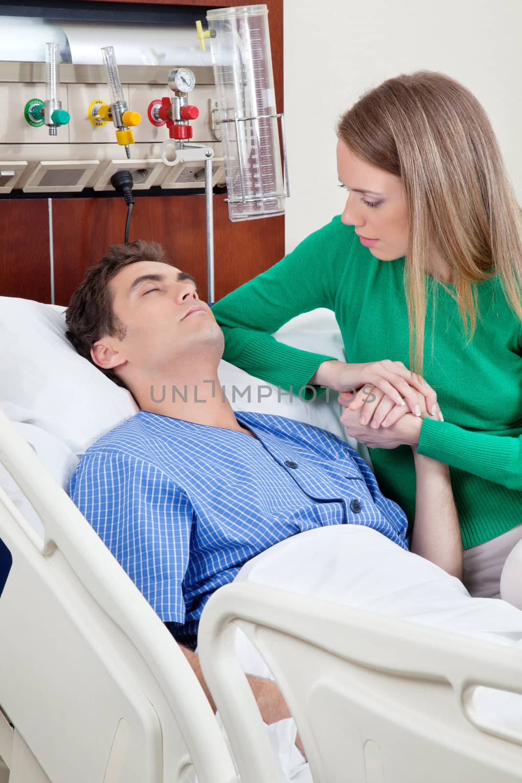 Caring wife holding hand of husband in hospital