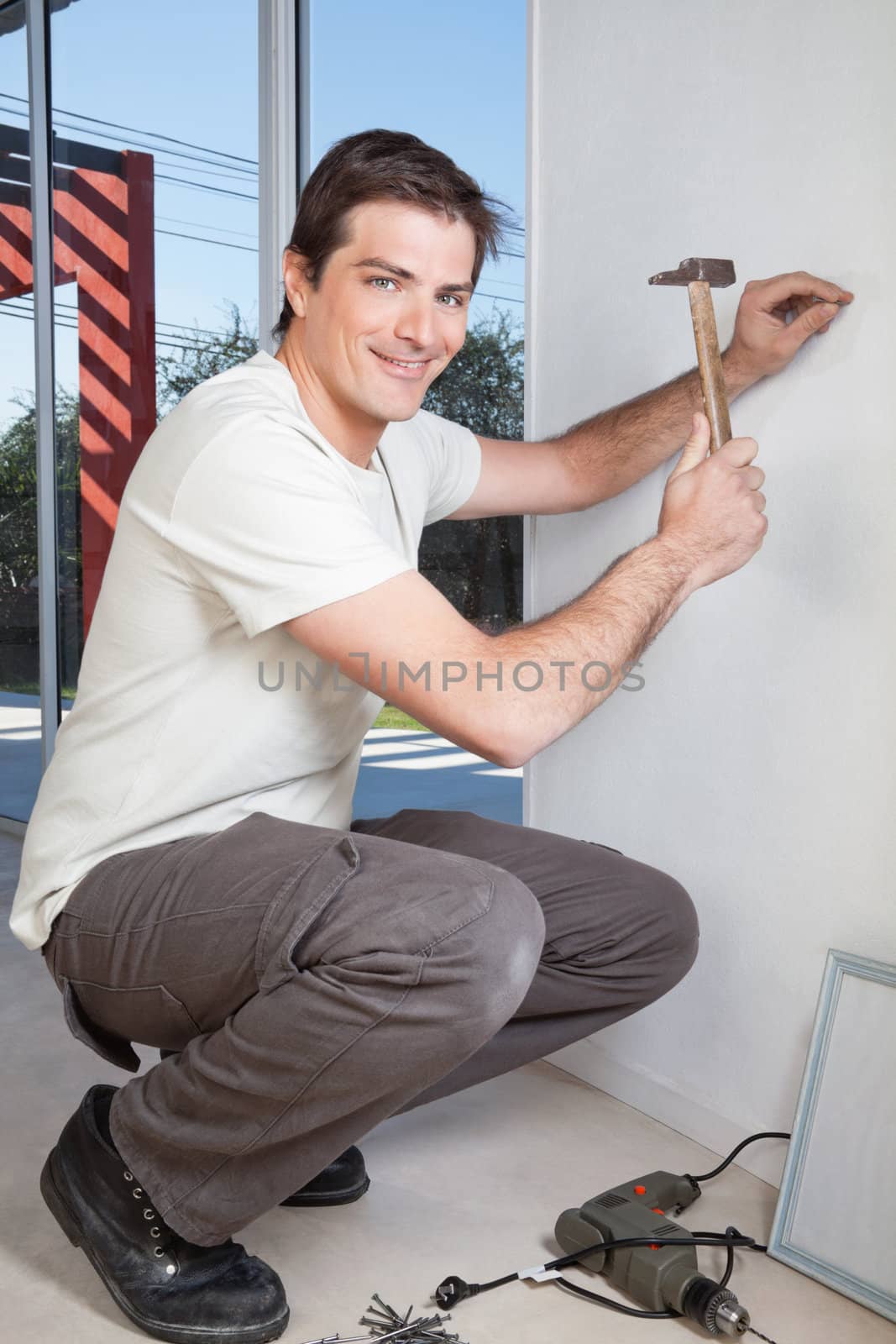 Young man with hammer nailing the wall