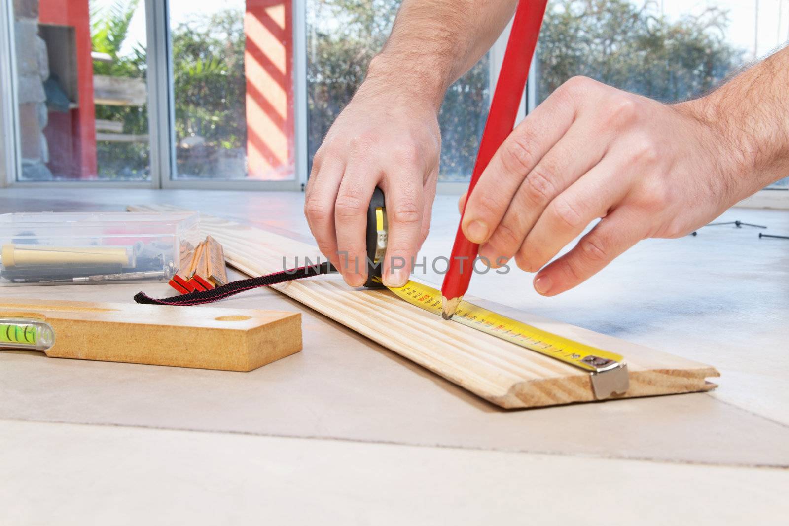 Close-up of engineer's hand marking on plywood with pencil and measuring