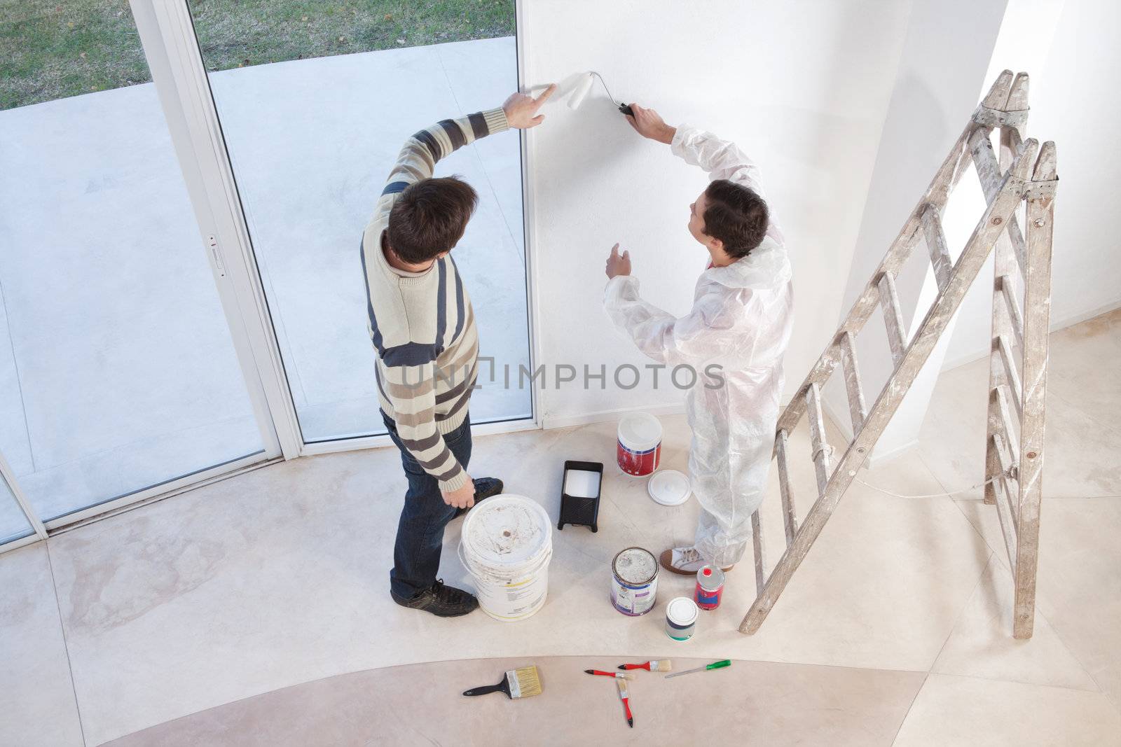 Young man showing a spot on the wall to painter