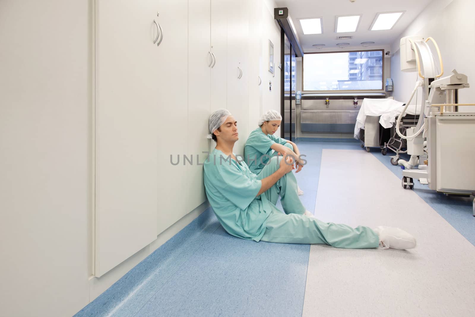 Two young doctors sitting in corridor tired after operation