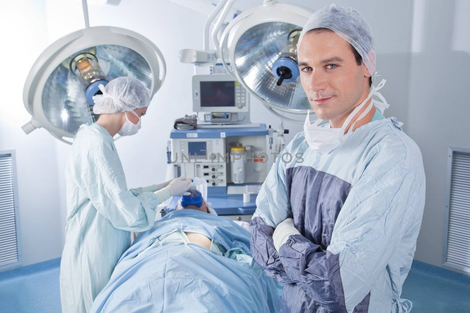 Smiling male doctor with arms crossed in operating room