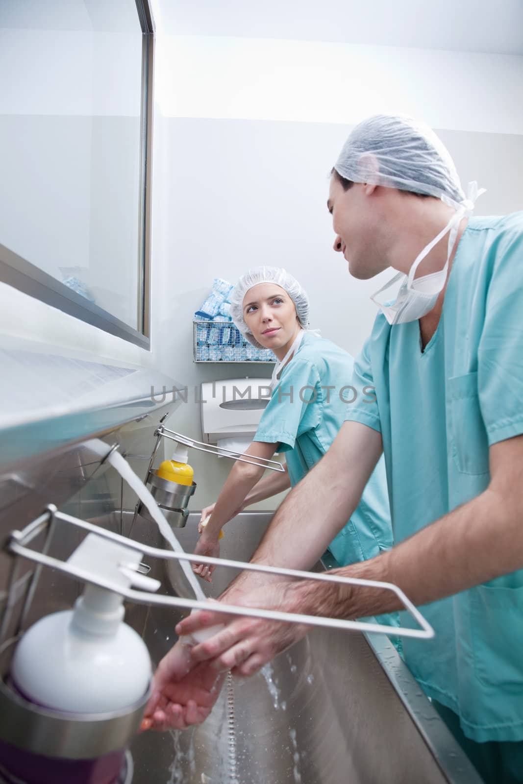 Young surgeons washing hands while talking after operation