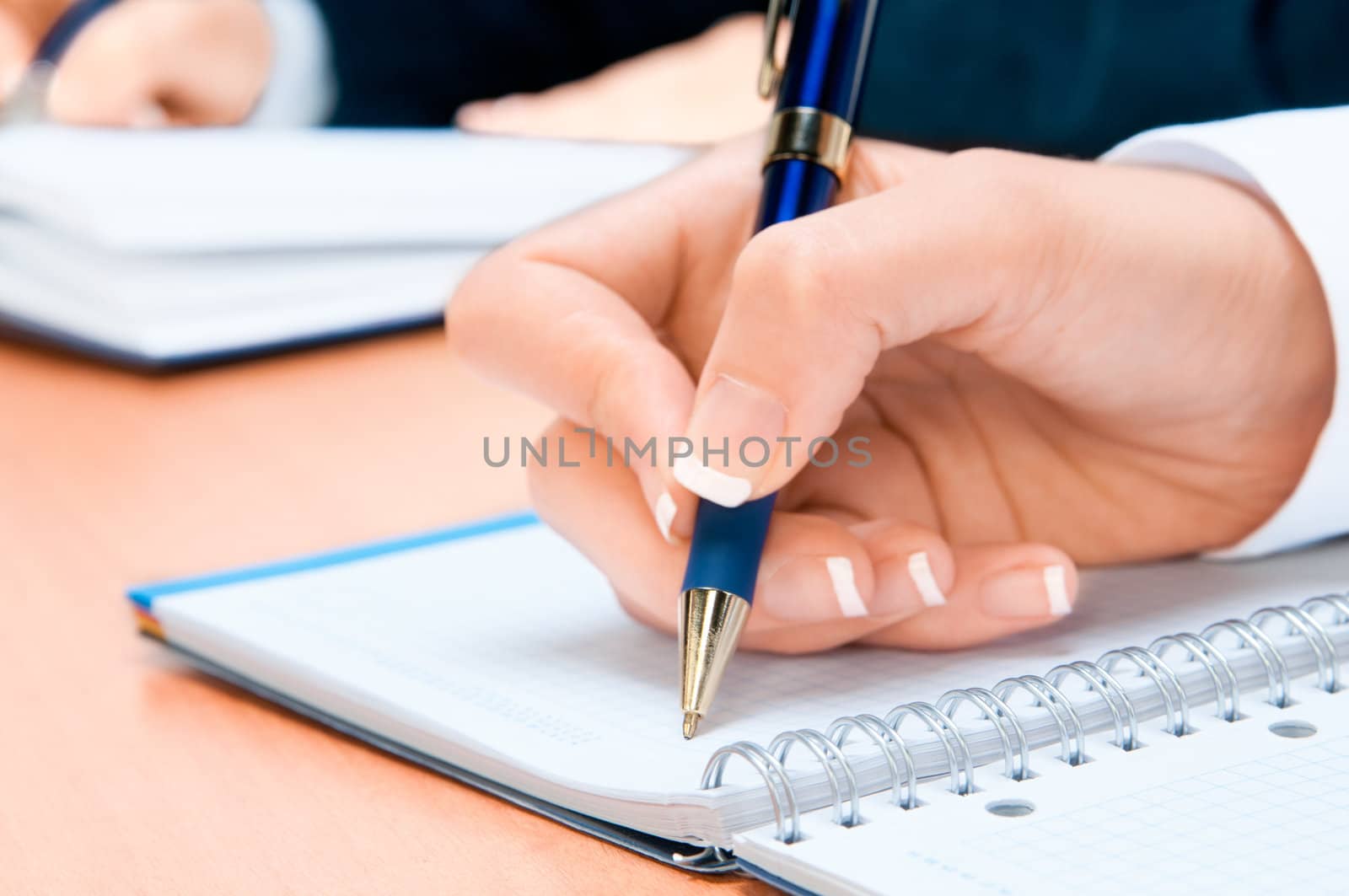 Cropped image of hand of young woman taking notes