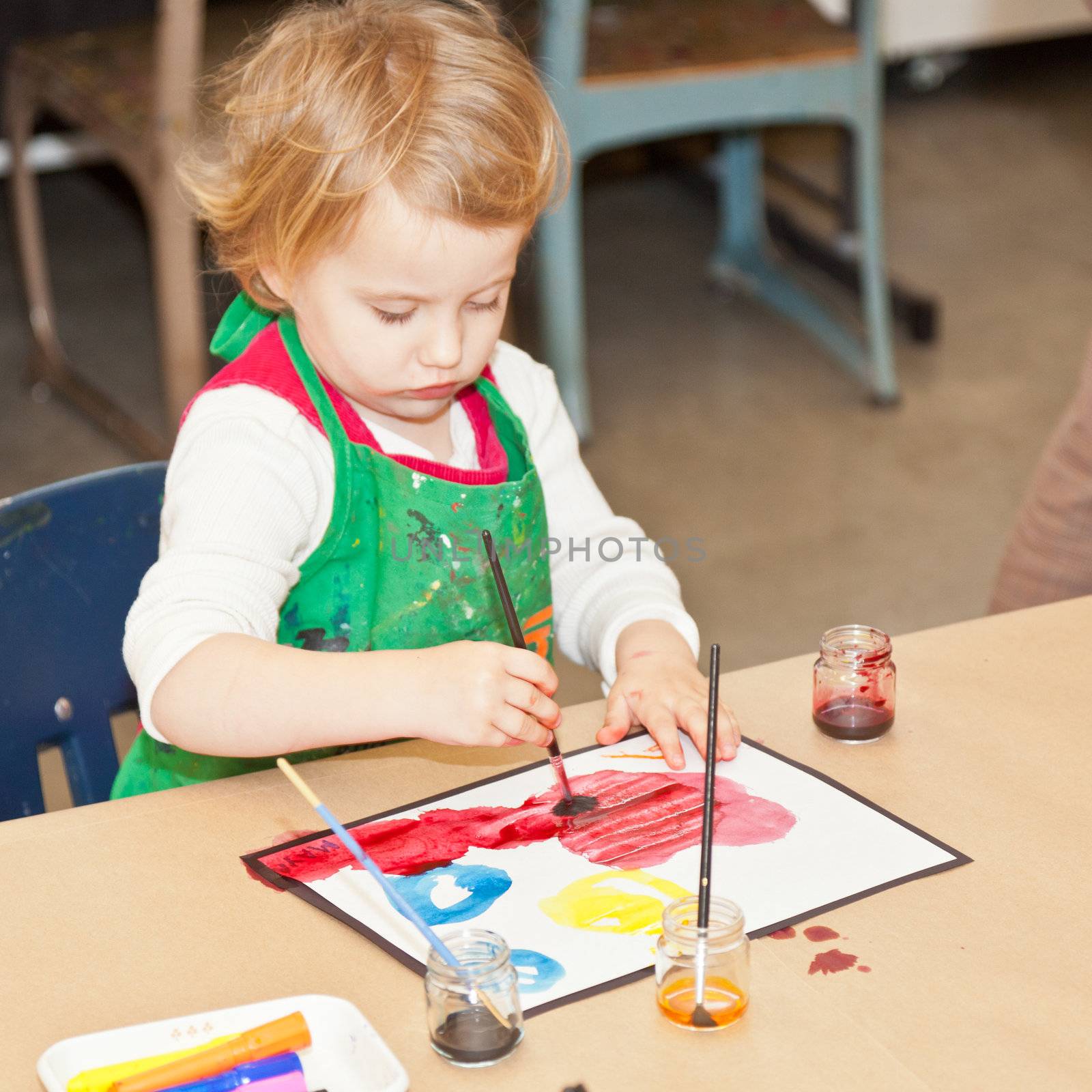 Cute little baby girl having fun painting at art class