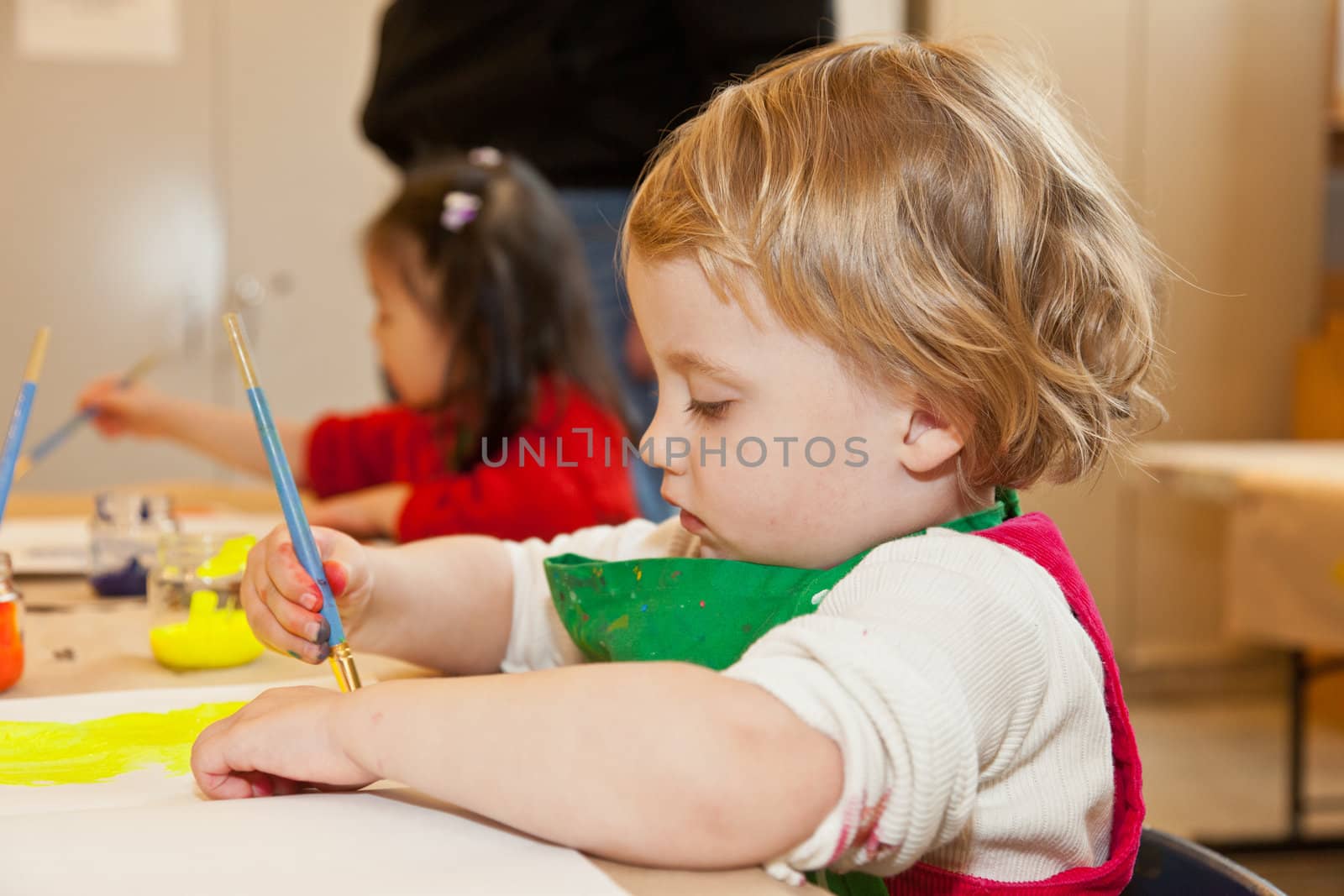 Cute little baby girl having fun painting at art class