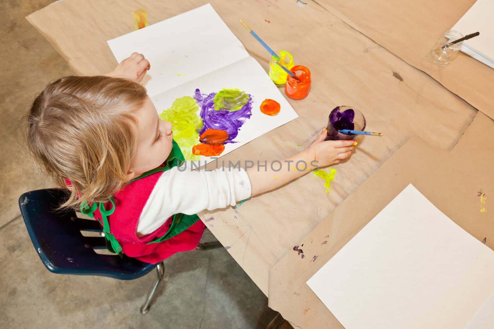 Cute little baby girl having fun painting at art class