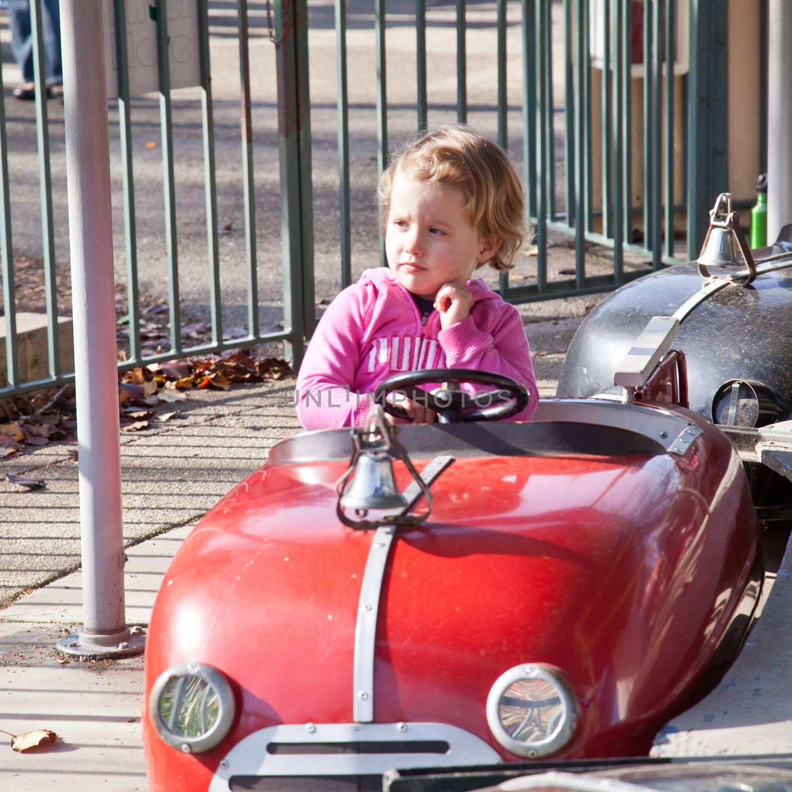 Cute little European girl having fun rinding on carousel.