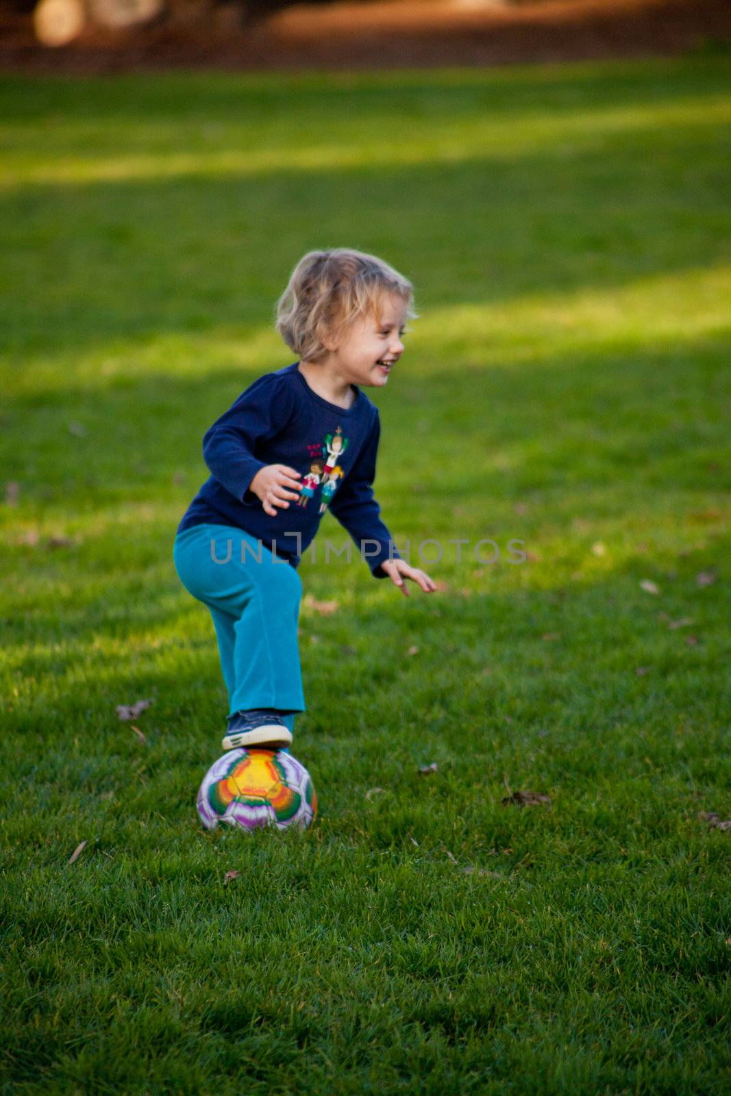 Cute little European girl having fun during soccer class in a park.
