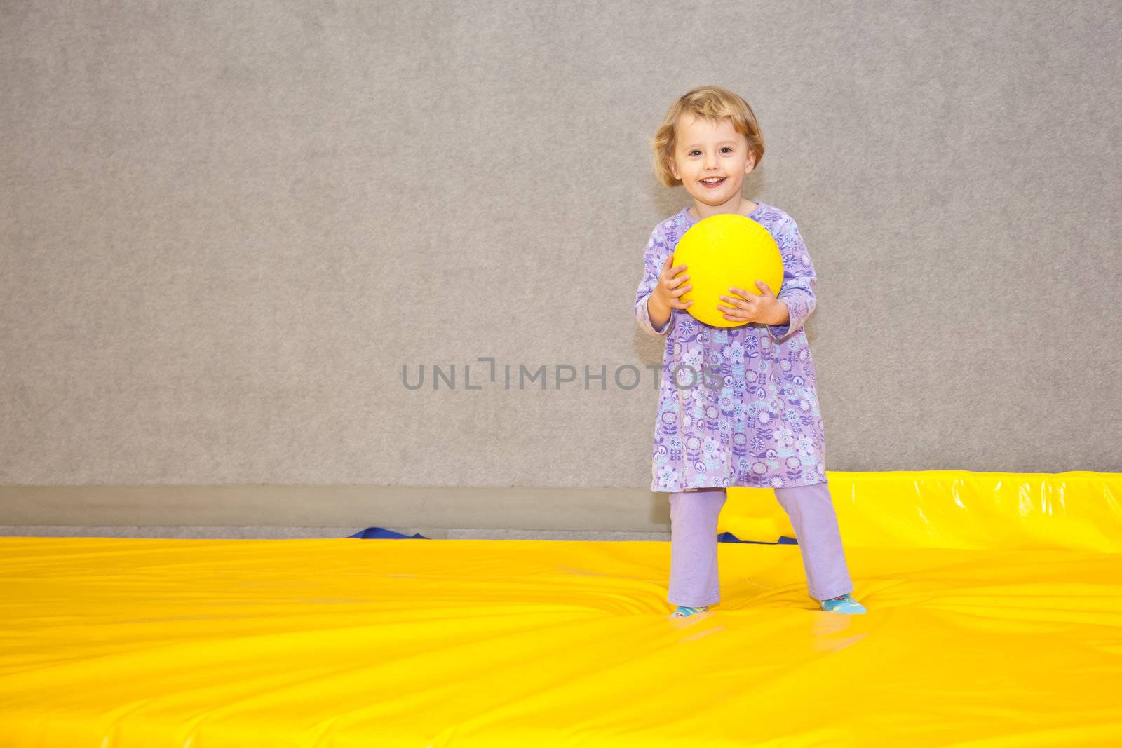 Cute little European toddler girl having fun at indoor playground.