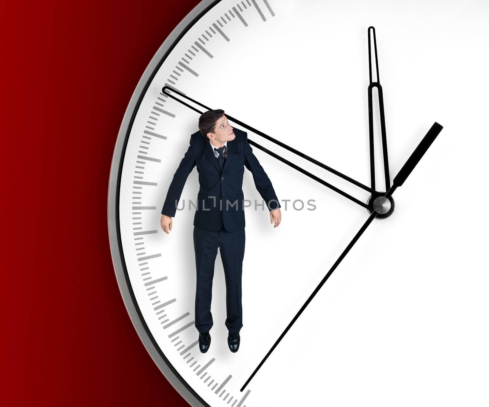 Businessman hangs on an arrow of clock, isolated on red background