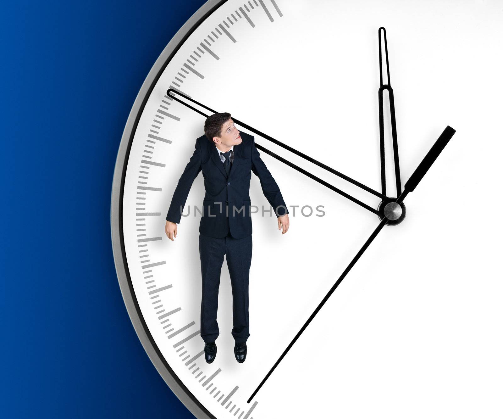 Businessman hangs on an arrow of clock, isolated on blue background