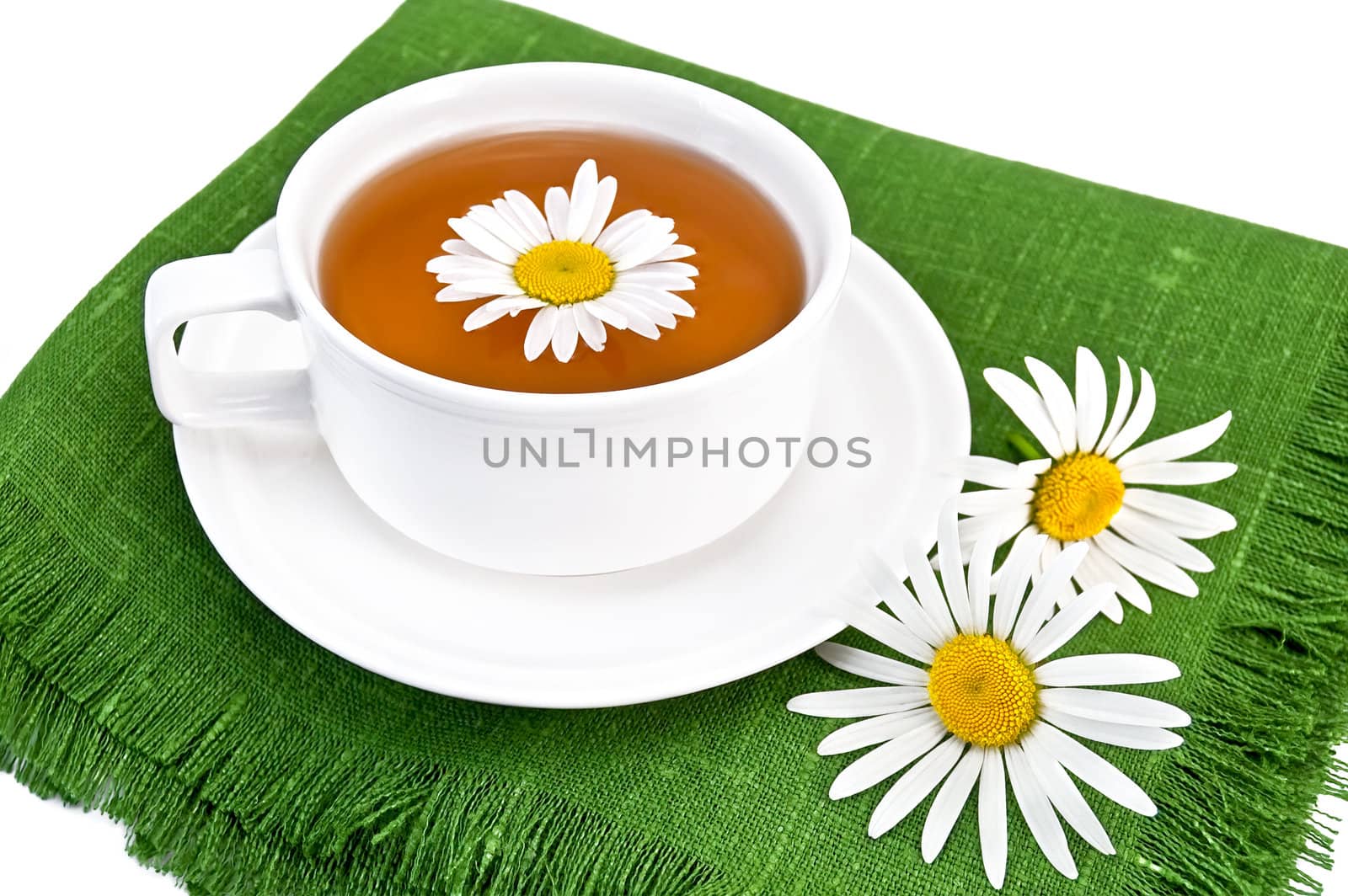 Herbal tea in a  white cup with daisies on the green napkin, isolated on a white background