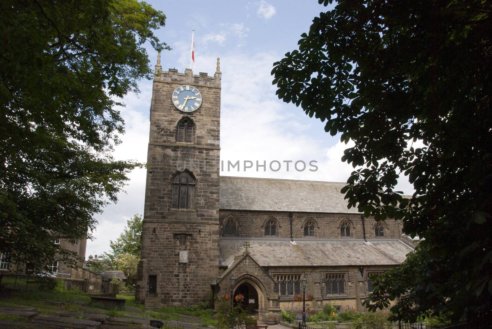 The Parish Church of St Michael and All Angels in Haworth Yorkshire under a blue summer sky