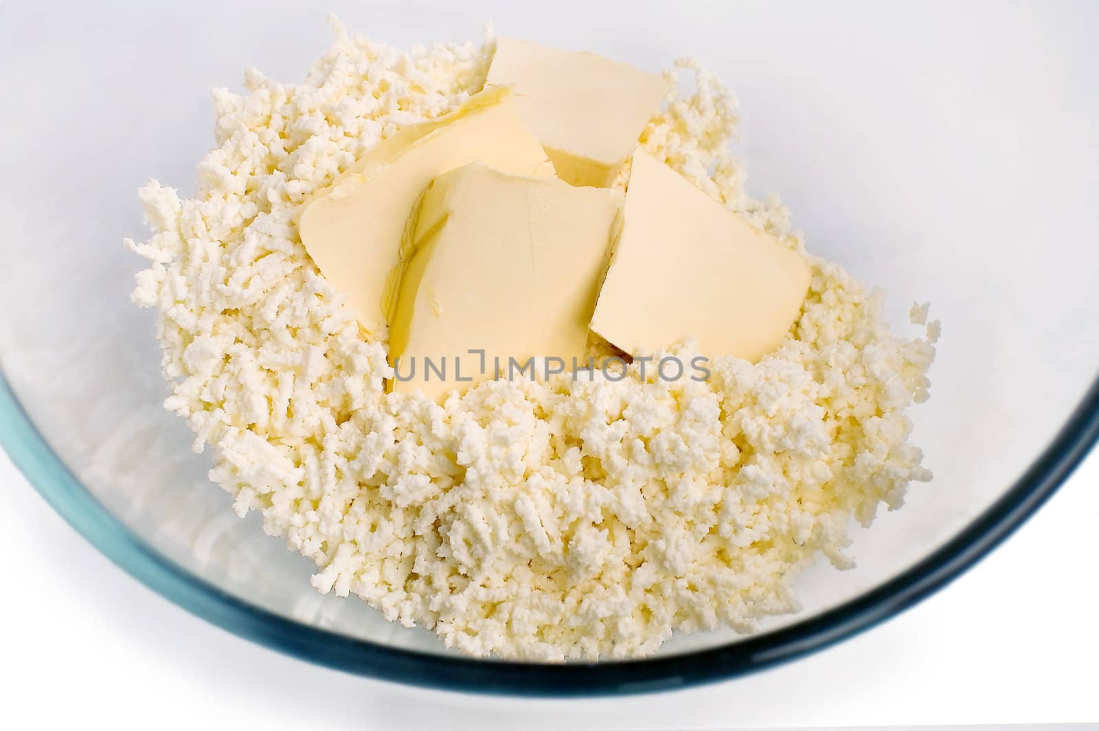 Grated curd, bits of butter in a glass dish in isolation on a white background