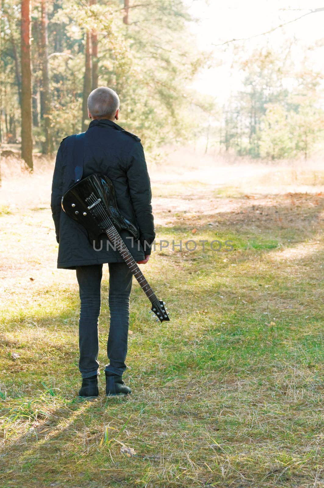 teen musician with a guitar in the autumn forest