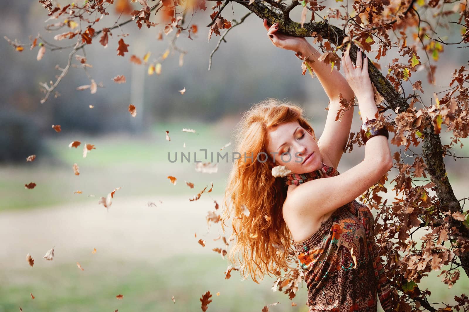 The red-haired girl in autumn leaves 
outdoor shot