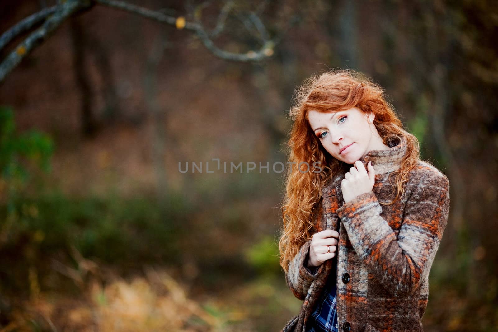 The red-haired girl in autumn leaves 
outdoor shot