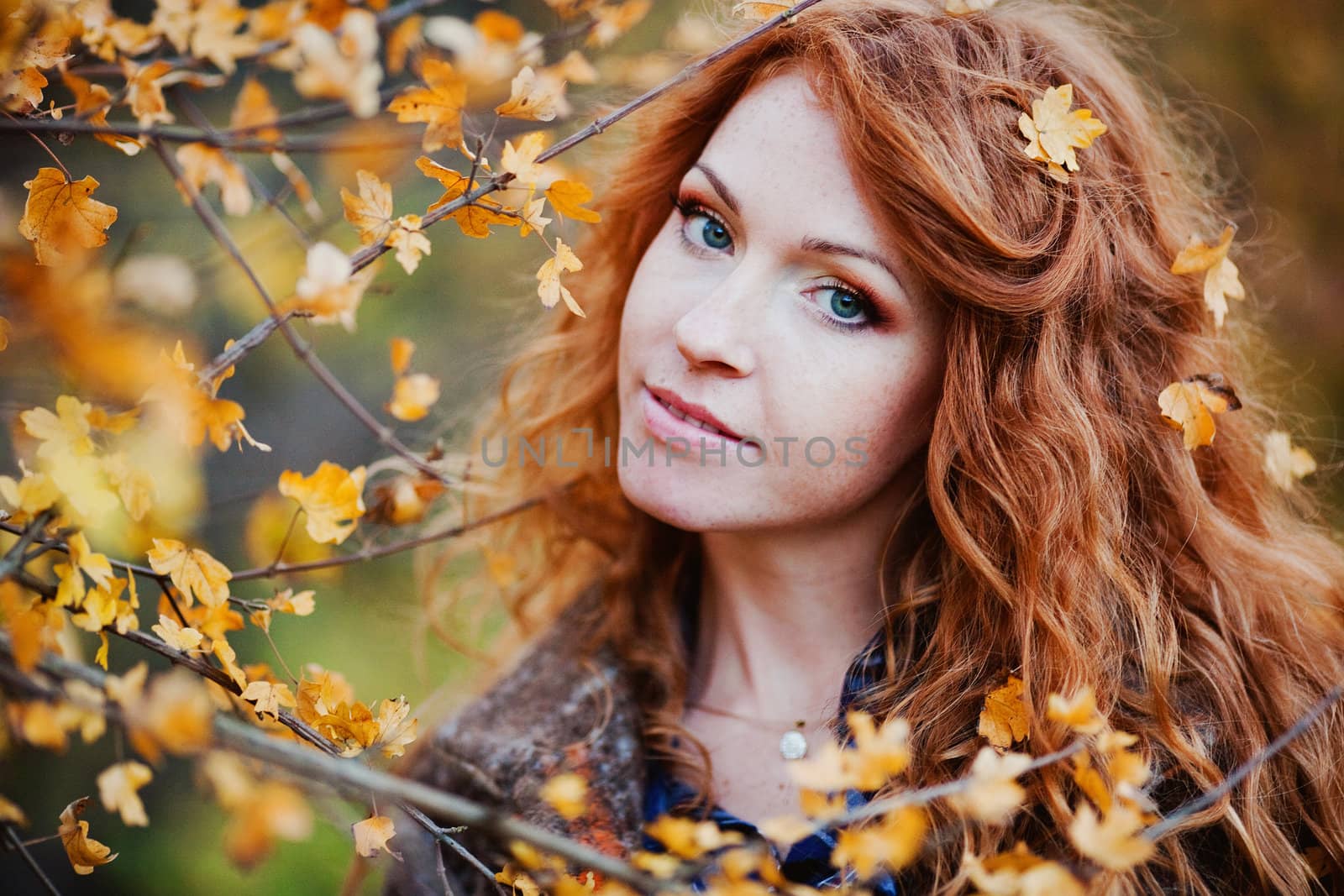 The red-haired girl in autumn leaves 
outdoor shot