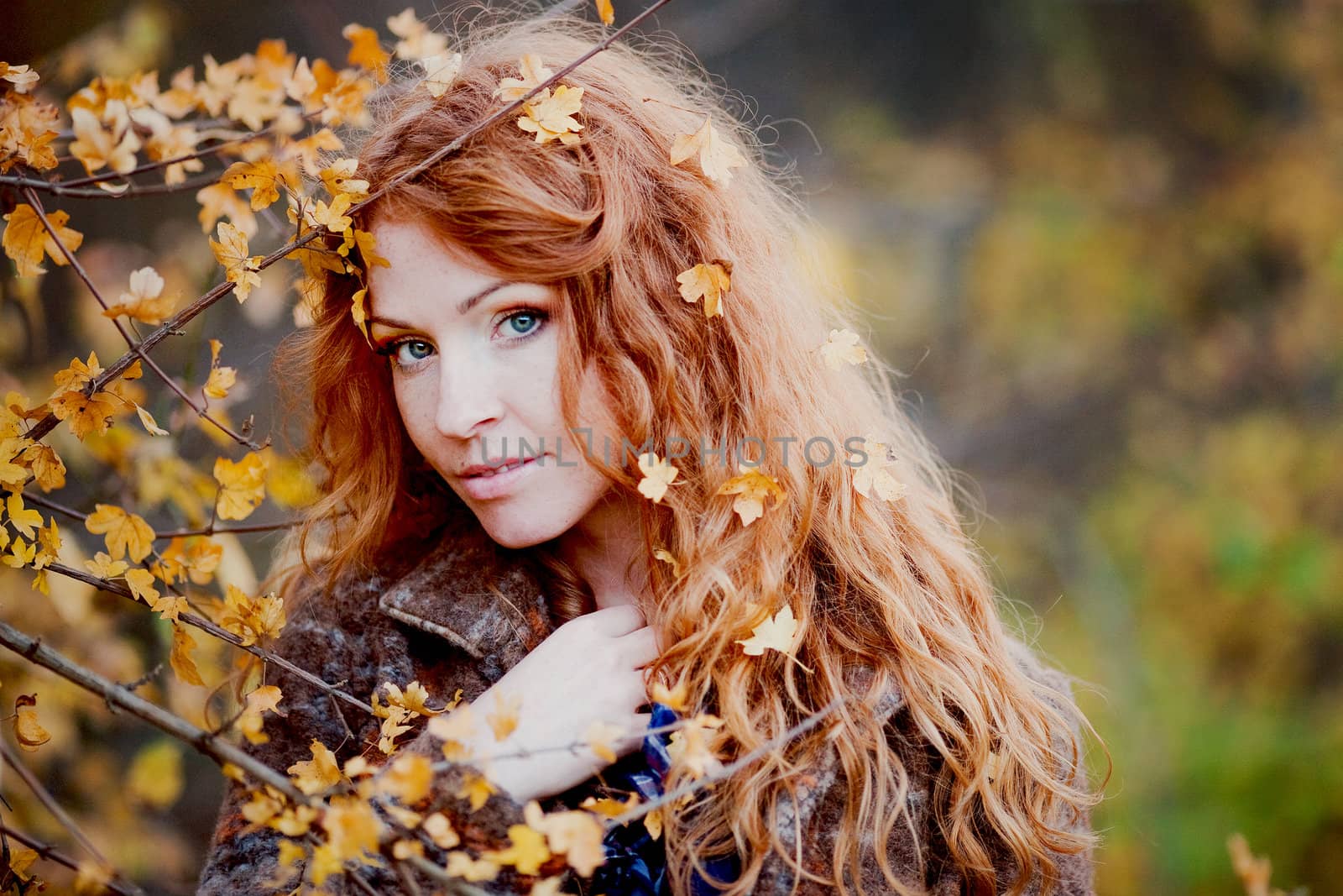 The red-haired girl in autumn leaves 
outdoor shot