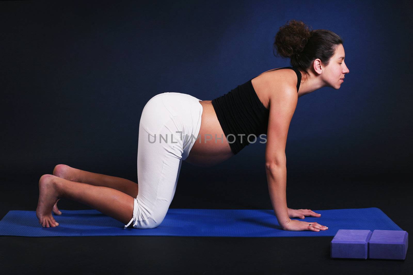 Beautiful pregnant  young woman practicing yoga on black