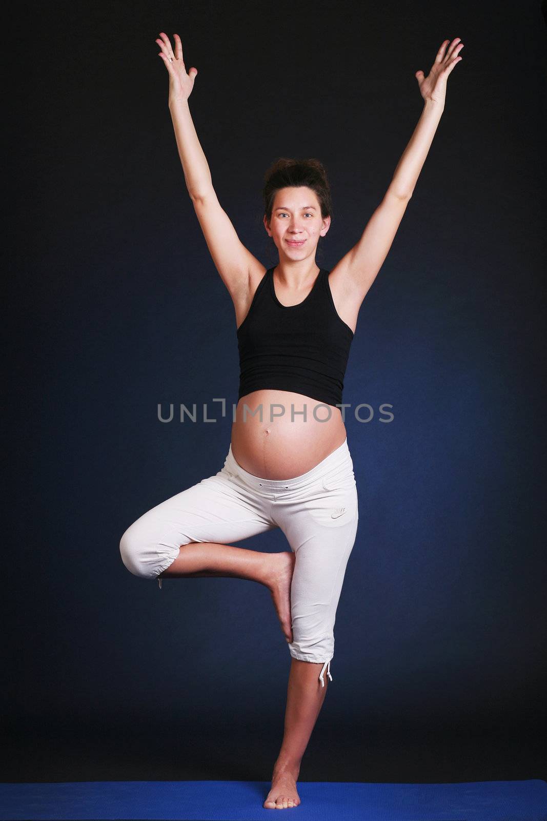 Beautiful pregnant  young woman practicing yoga on black