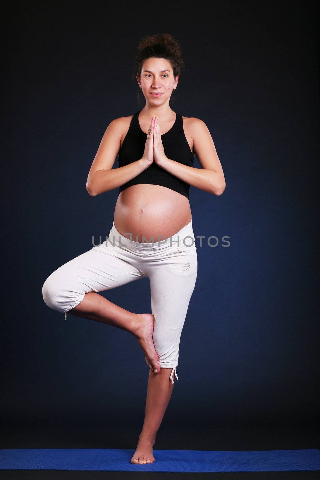 Beautiful pregnant  young woman practicing yoga on black