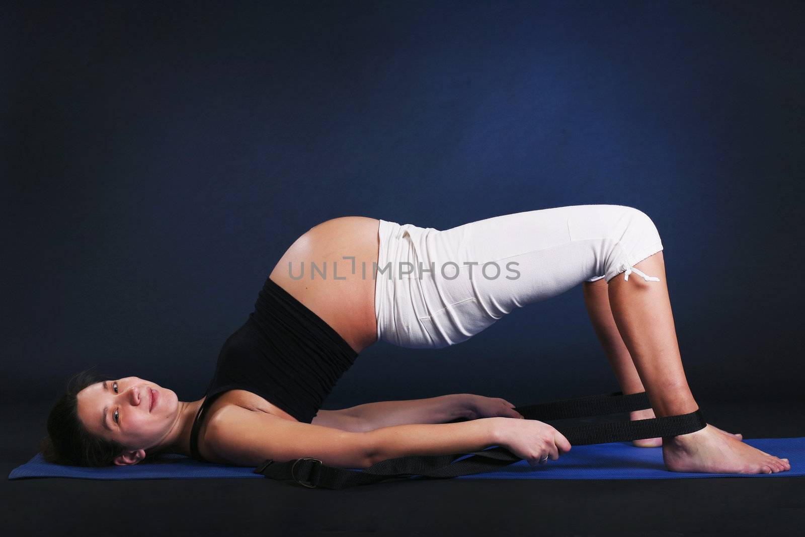 Beautiful pregnant  young woman practicing yoga on black