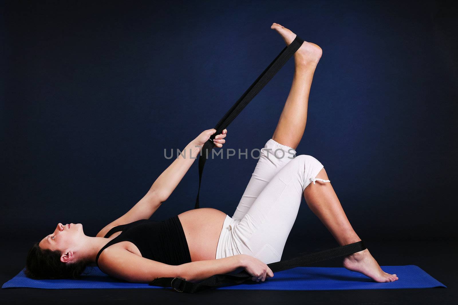 Beautiful pregnant  young woman practicing yoga on black