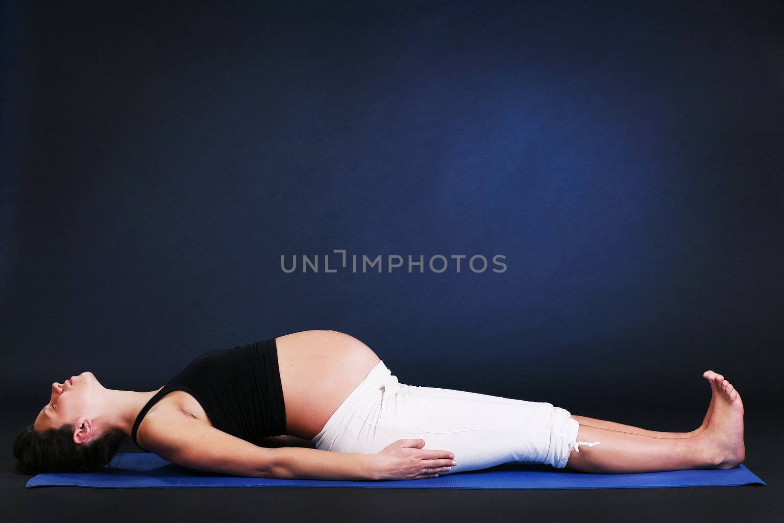 Beautiful pregnant  young woman practicing yoga on black