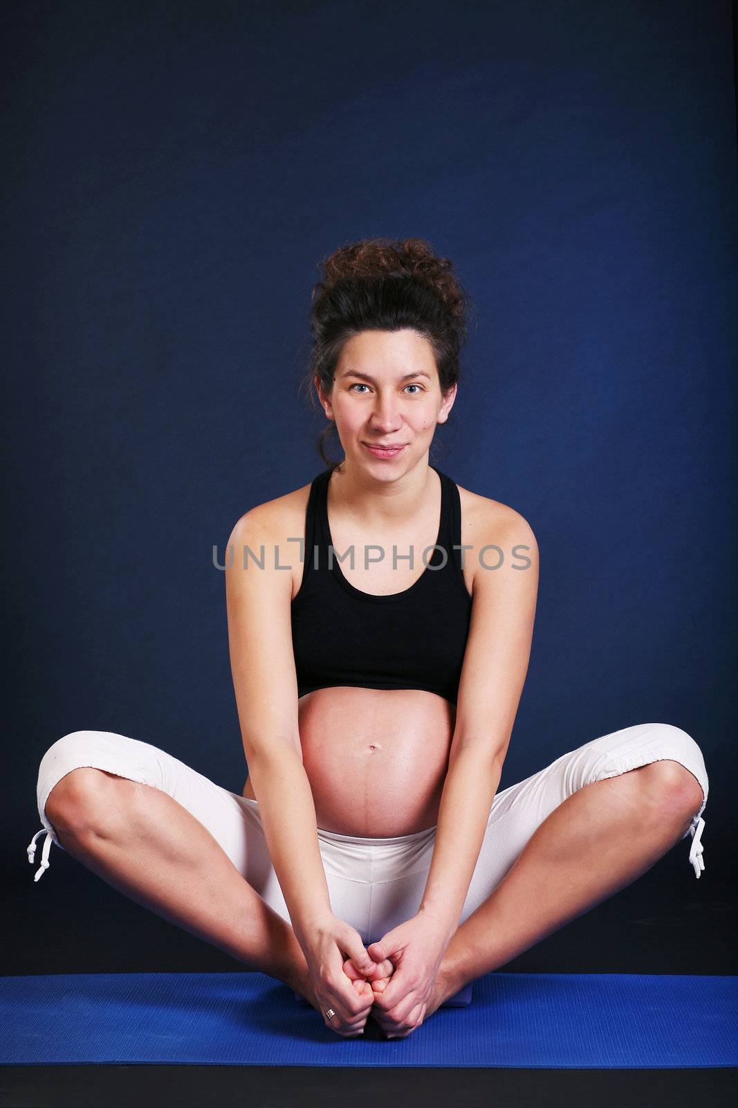 Beautiful pregnant  young woman practicing yoga on black