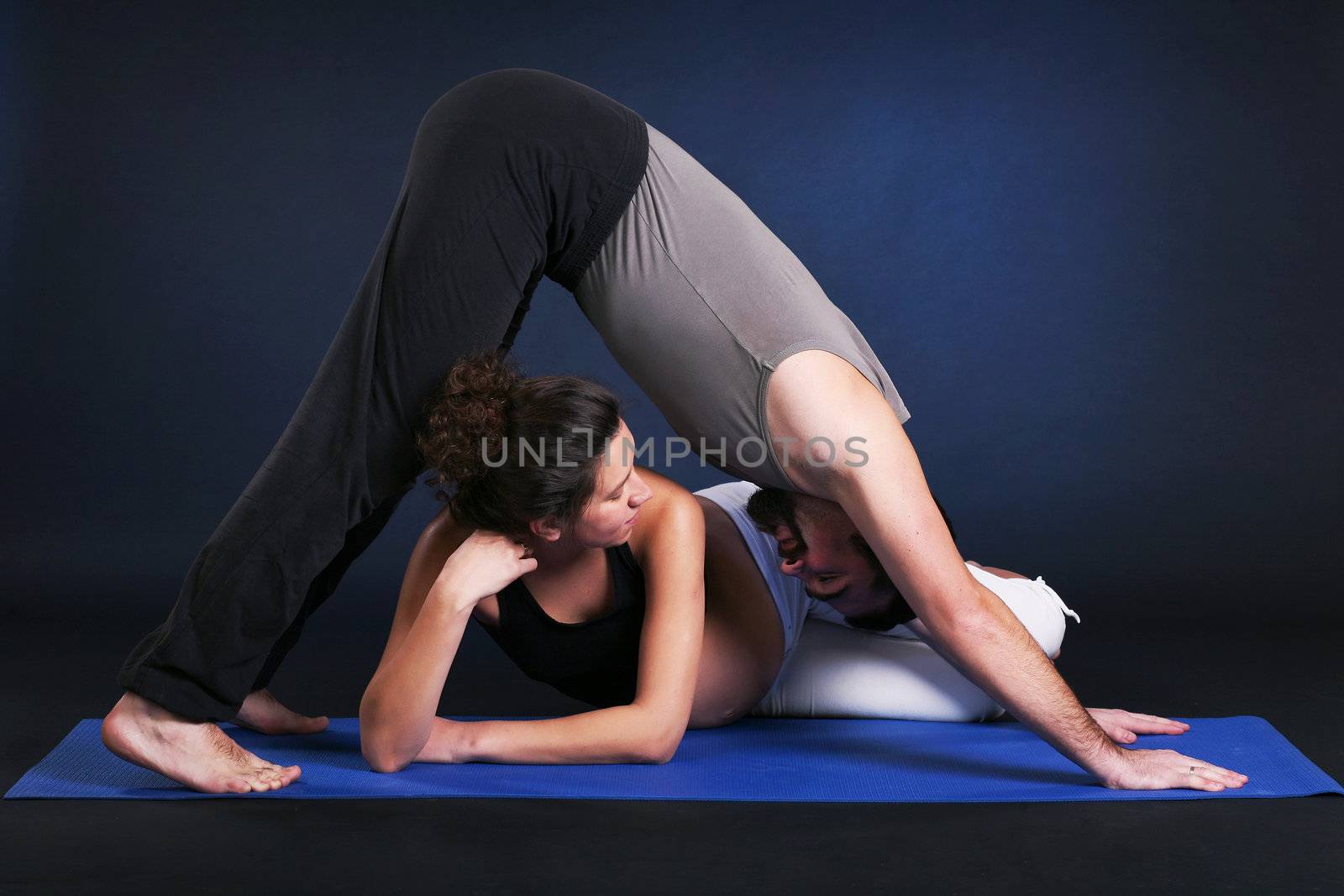 Beautiful pregnant  young woman practicing yoga with husband