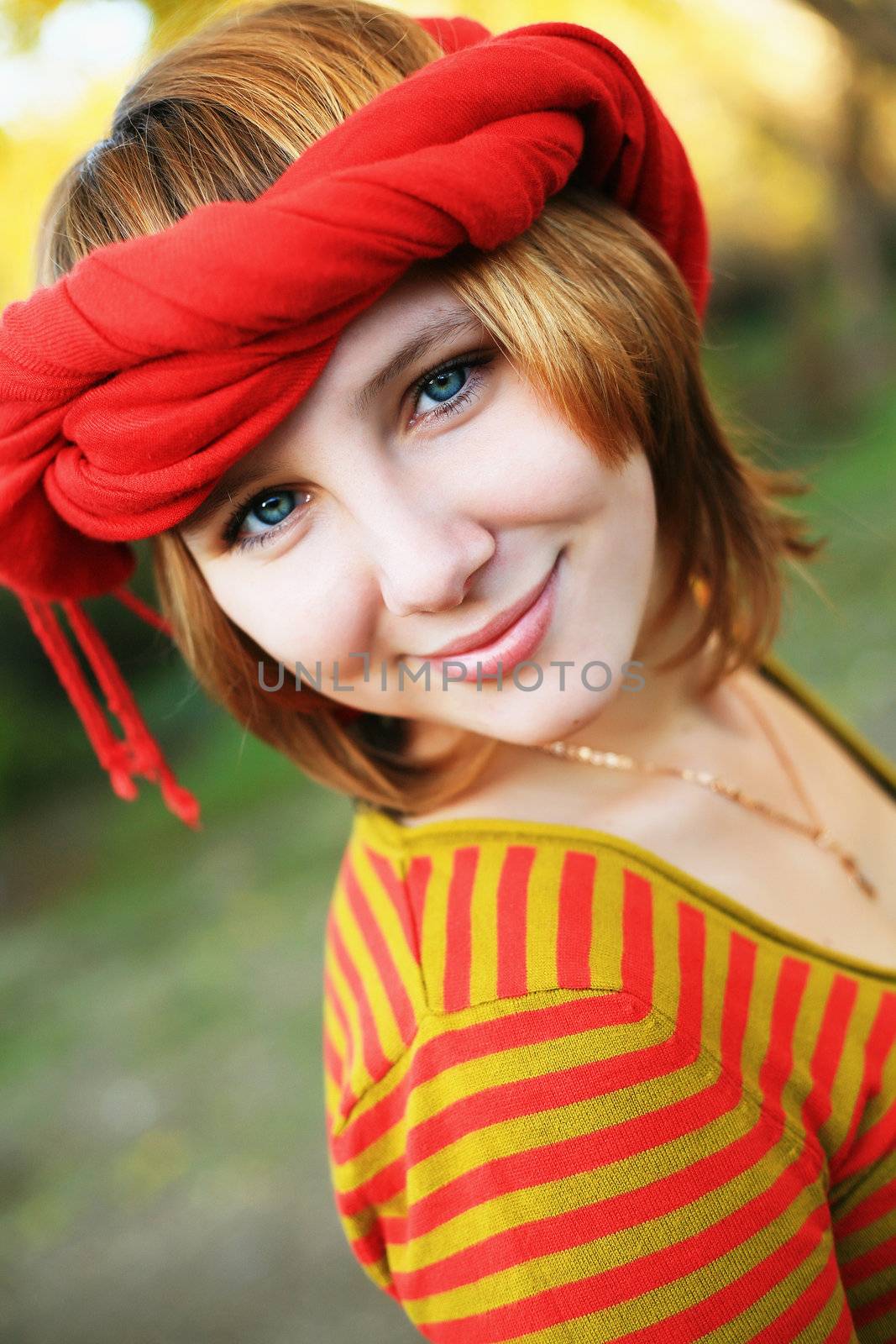 portrait of a girl in a bright colored striped sweater lying on the grass