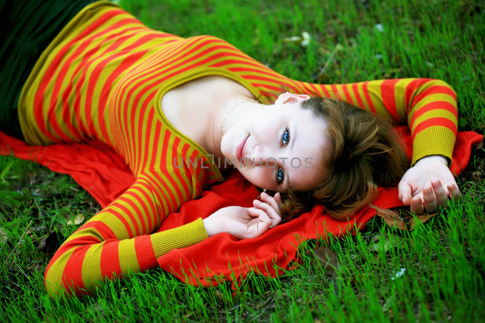 portrait of a girl in a bright colored striped sweater lying on the grass