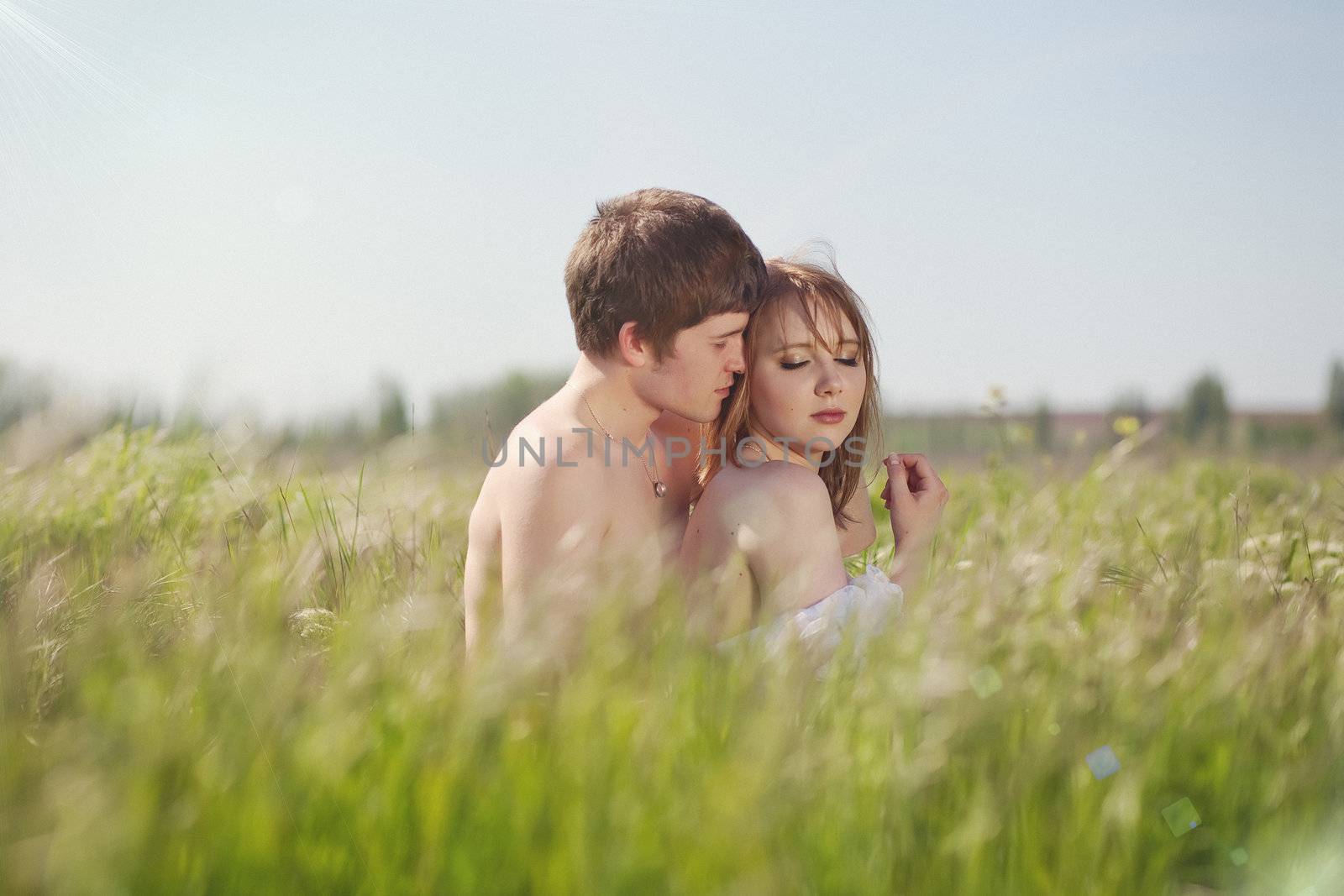 beautiful young pair kissing and hugging on green grass