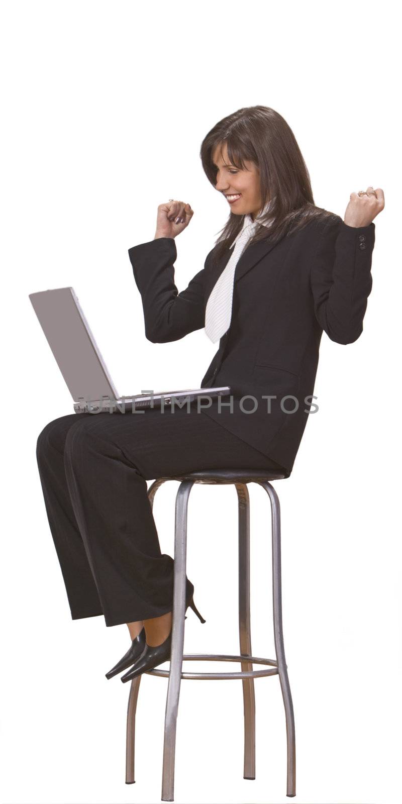 Businesswoman expressing satisfaction in front of a laptop while she is sitting on a high chair.